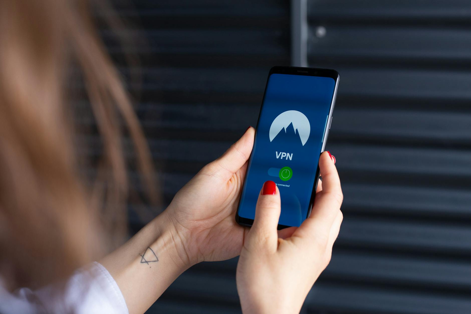 VPN dla początkujących: co daje i jak wybrać bez wpadek Dłonie kobiety uruchamiającej aplikację VPN na smartfonie