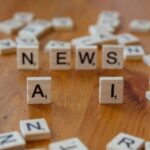 Drewniane płytki Scrabble układające się w napisy AI i NEWS