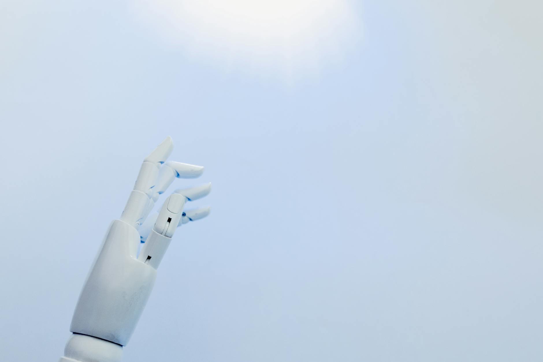 Robotyczna dłoń sięgająca po jasne światło na białym tle