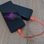 Smartfon ładowany powerbankiem kablem USB C na drewnianym stole
