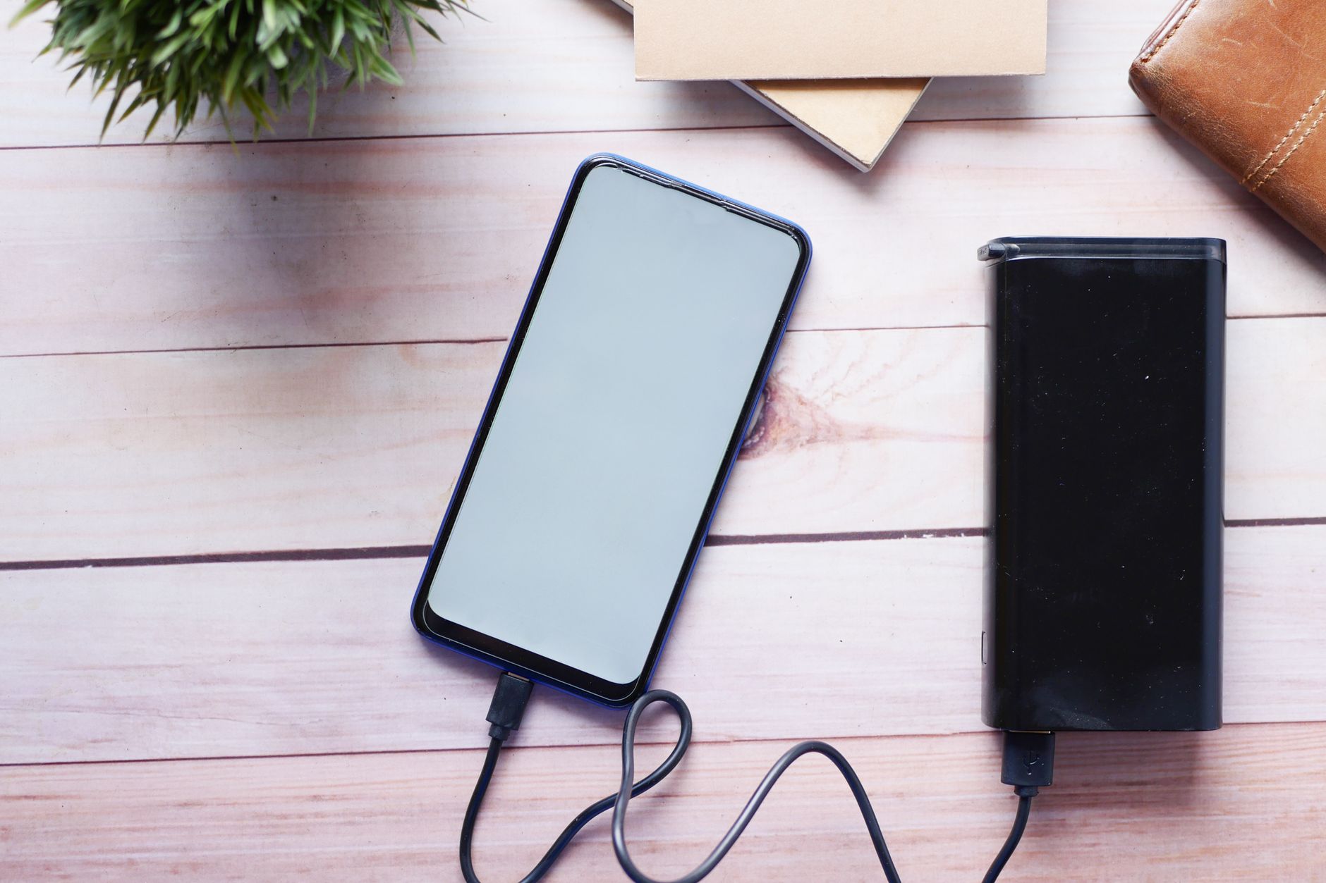 Smartfon ładowany powerbankiem USB C na drewnianym biurku