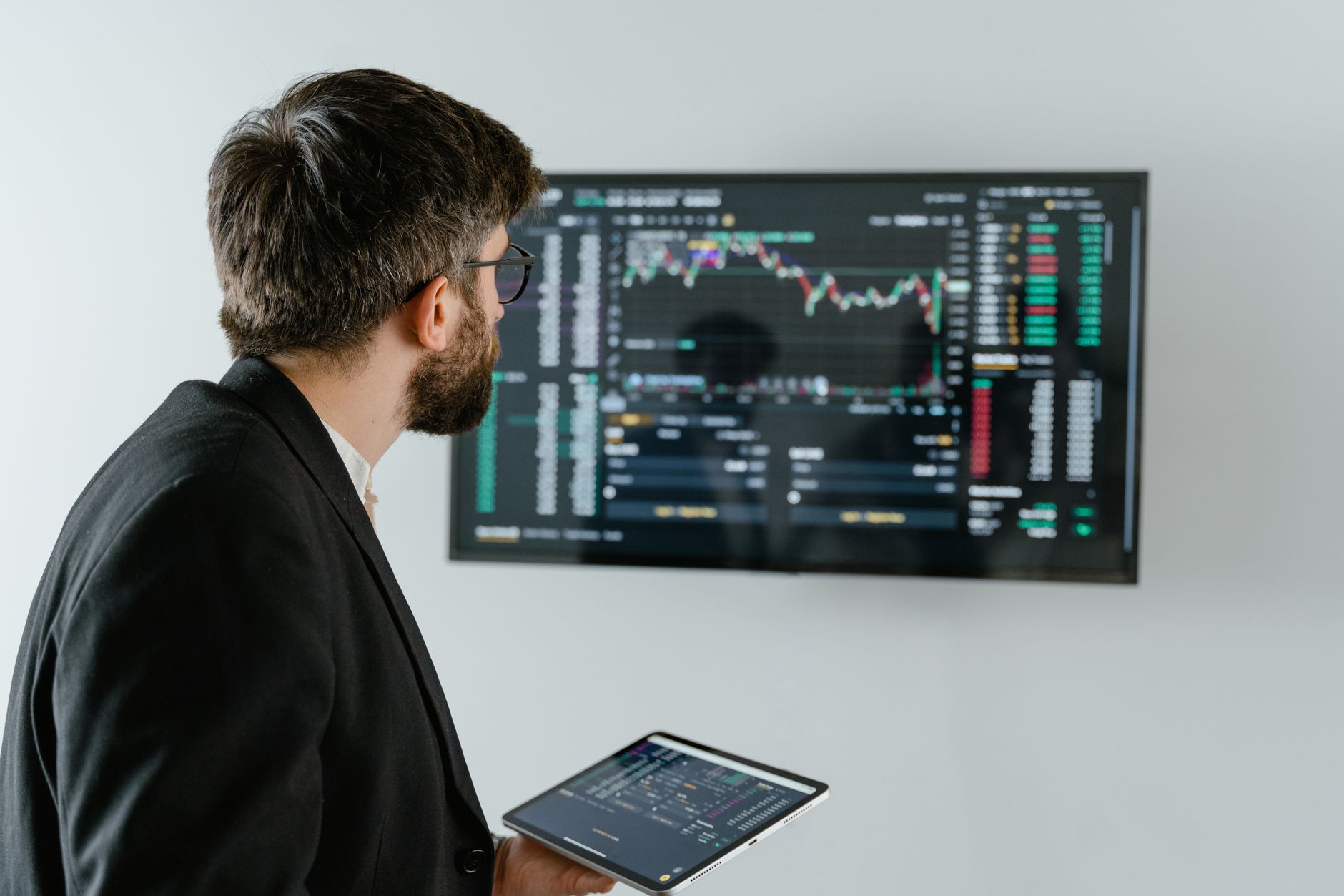Biznesmen analizuje dane giełdowe na monitorze i tablecie