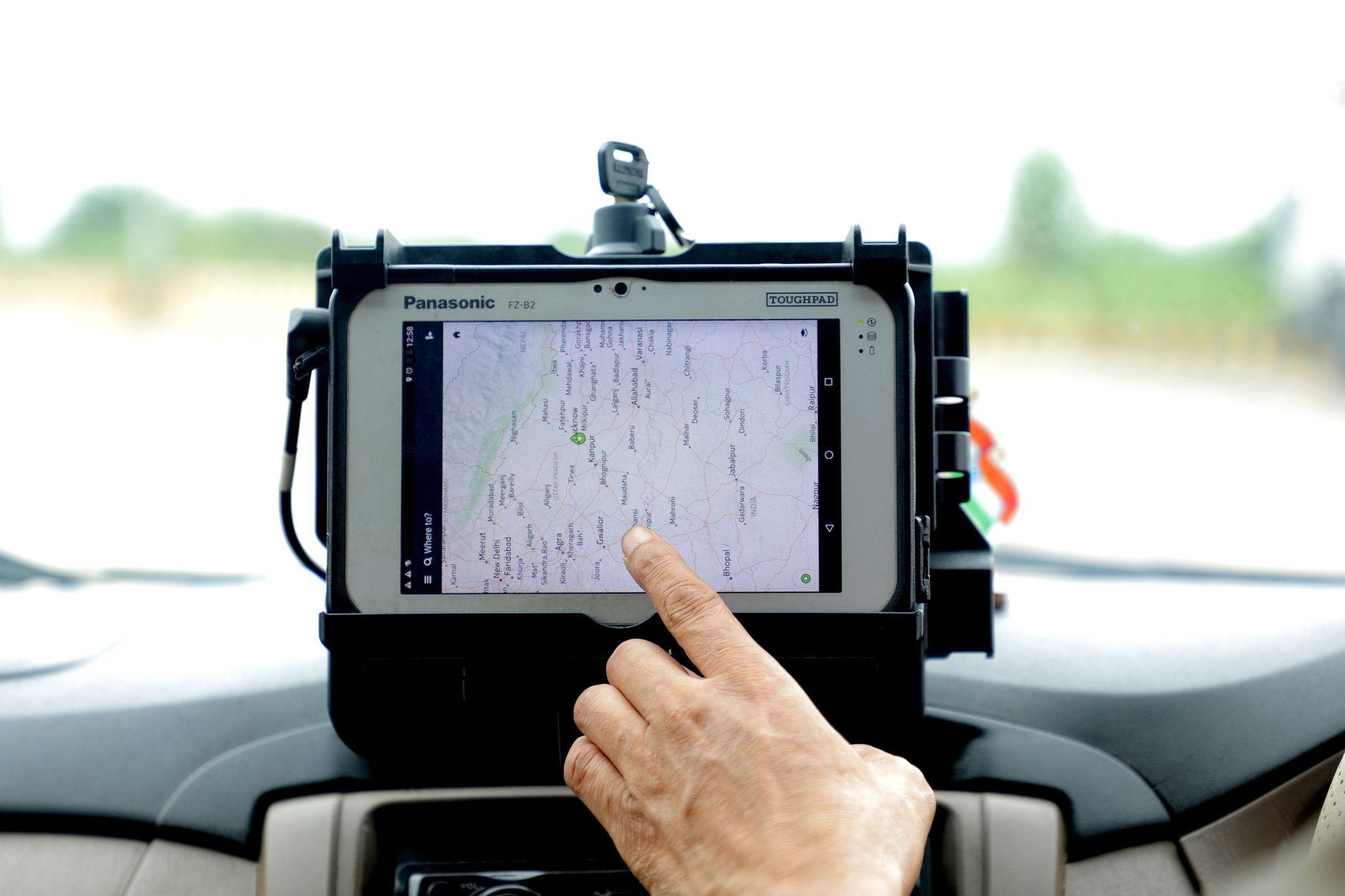 Tani tracker GPS IoT: jak działa, ile kosztuje i na co uważać przy abonamencie Dłoń obsługująca nawigację GPS na tablecie zamontowanym w aucie
