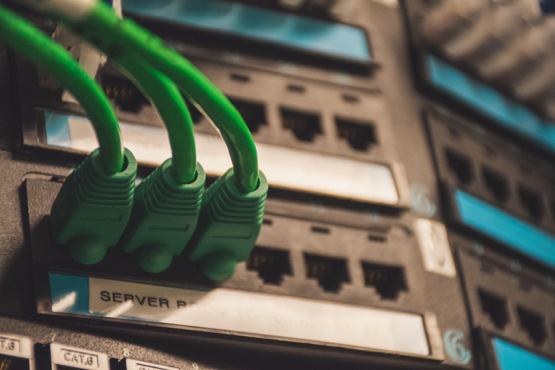 Zielone kable sieciowe podłączone do portów serwera w centrum danych